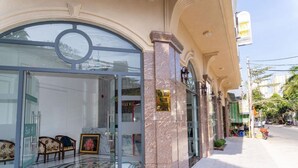 L’entrée d’un hôtel, avec une porte en verre, un comptoir d’accueil et une enseigne indiquant le nom de l’hôtel.