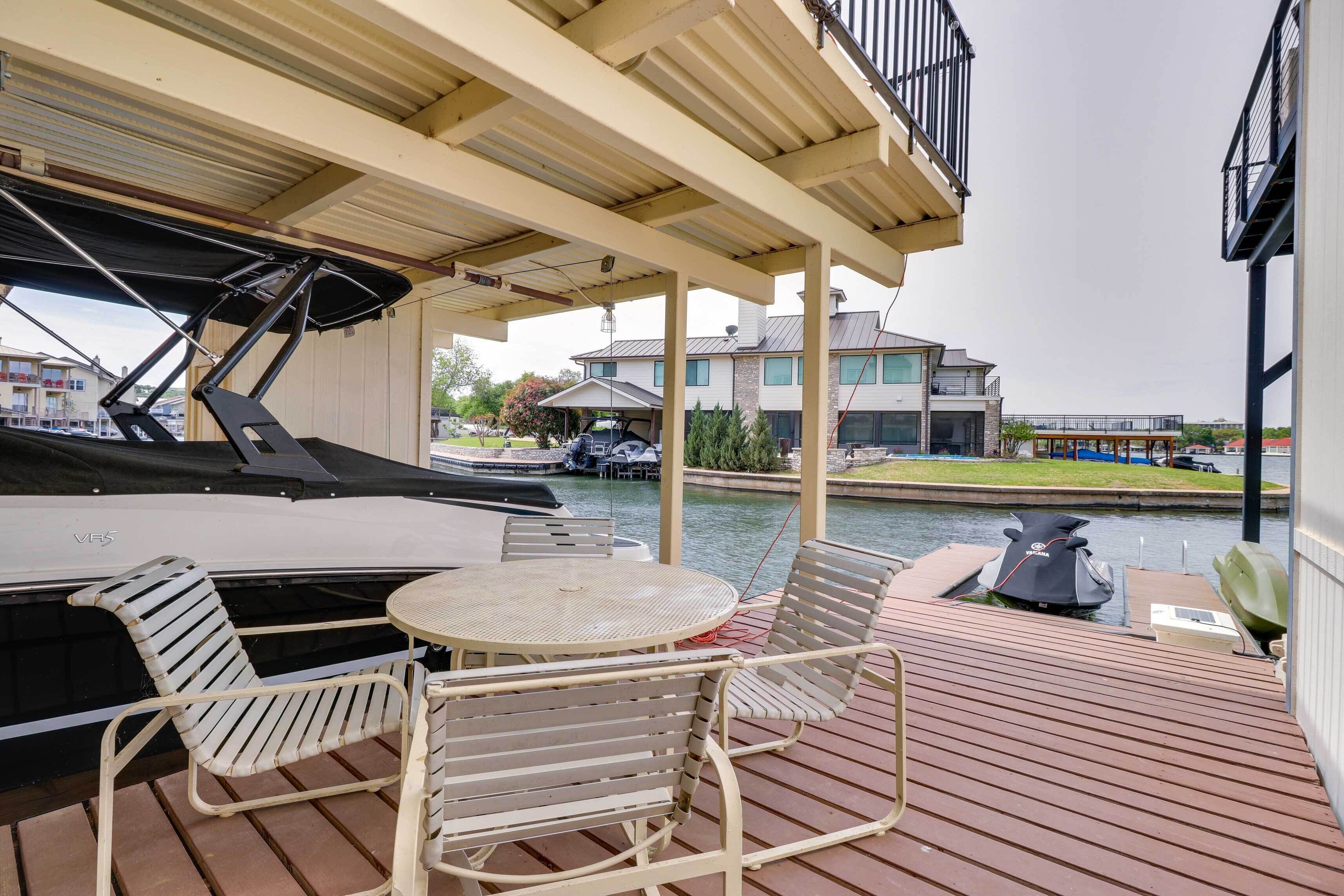 A covered outdoor deck with a table and chairs, a boat, and a view of a canal and buildings.