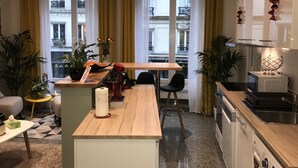 Una cocina moderna con encimera de madera, un comedor con sillas y vistas a la ciudad a través de amplios ventanales.