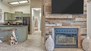 Una cucina moderna con isola centrale, una TV a schermo piatto montata su una parete in legno e un camino.