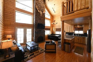 Cozy living area with fireplace, comfortable seating, and dining space, featuring a kitchen in the background.