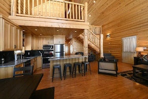 Cozy cabin interior with a mezzanine level, kitchen, and comfortable living space.