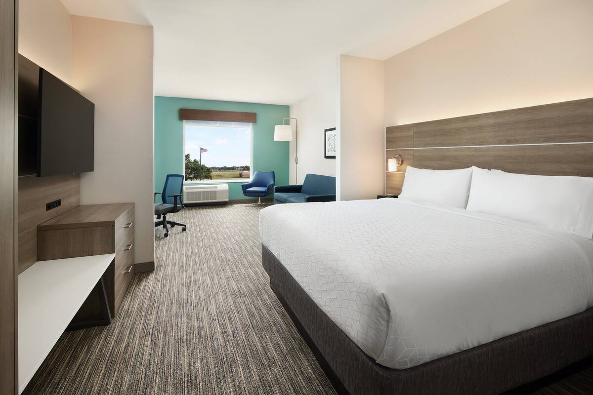Une chambre d’hôtel avec un grand lit, un bureau, une chaise et un téléviseur.
