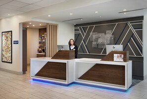A hotel reception desk with a modern design, a digital display, and a sign for the express shop.