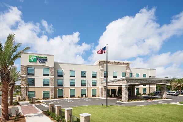 Een hotel met een modern design, met een opvallende Amerikaanse vlag en een bord voor Hilton Express & Suites.