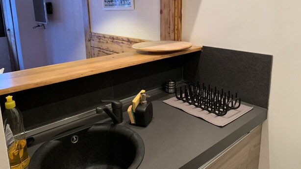 A modern kitchen with a black sink, wooden countertop, and a wooden shelf. - Cosy 2-room apartment in the heart of Chamonix, Mont Blanc view (Chamonix-Mont-Blanc)