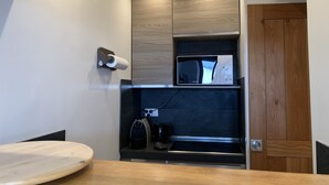 A compact kitchen with a microwave, coffee maker, and a wooden door. - Cosy 2-room apartment in the heart of Chamonix, Mont Blanc view (Chamonix-Mont-Blanc)