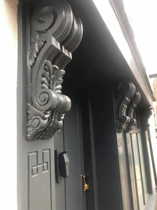 Une porte noire ornée de motifs métalliques et dotée d’une serrure moderne.