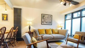 A living room with a sofa, chairs, a radiator, and artwork on the walls.