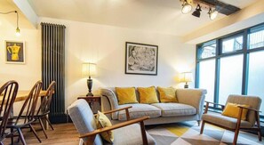 A 3-bedroom apartment with a sofa, chairs, a dining table, and artwork on the walls.