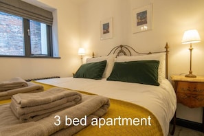 Apartamento de tres habitaciones con cama, almohadas, mesita de noche y ventana.