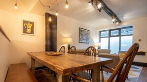 A dining area with a wooden table and chairs, a lamp, and artwork on the walls. - Heart of Macclesfield Former 16th Century Inn (Macclesfield)