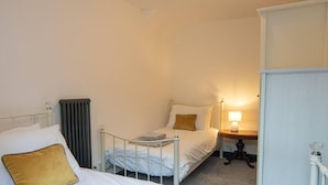 Une petite chambre individuelle comprenant un lit, une table de chevet et un radiateur.