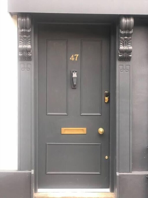 A dark grey door with the number 47, a mail slot, a doorbell, and a keyhole.
