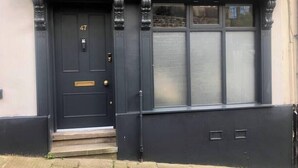 A dark-colored front door with a number plate, a small set of steps, and a window with frosted glass. - Heart of Macclesfield Former 16th Century Inn (Macclesfield)