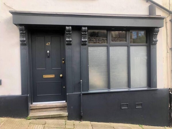 A dark-colored front door with a number plate, a small set of steps, and a window with frosted glass.
