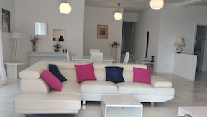 Ein modernes Wohnzimmer mit einem weißen modularen Sofa, einem Couchtisch und Pendelleuchten.