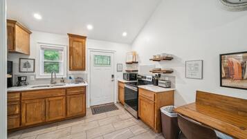 A modern kitchen with wooden cabinets, a microwave, stove, and a dining area with a table and chairs.