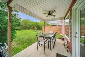 A covered patio with a glass table and chairs, a ceiling fan, and a view of a grassy yard and neighboring buildings. - GrandLake*Kayak*ForestView*Firepit*Kings*Lakefront (Grove)