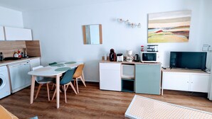 Eine kleine Küche mit Essbereich, einer Mikrowelle, einer Kaffeemaschine und einem Fernseher.