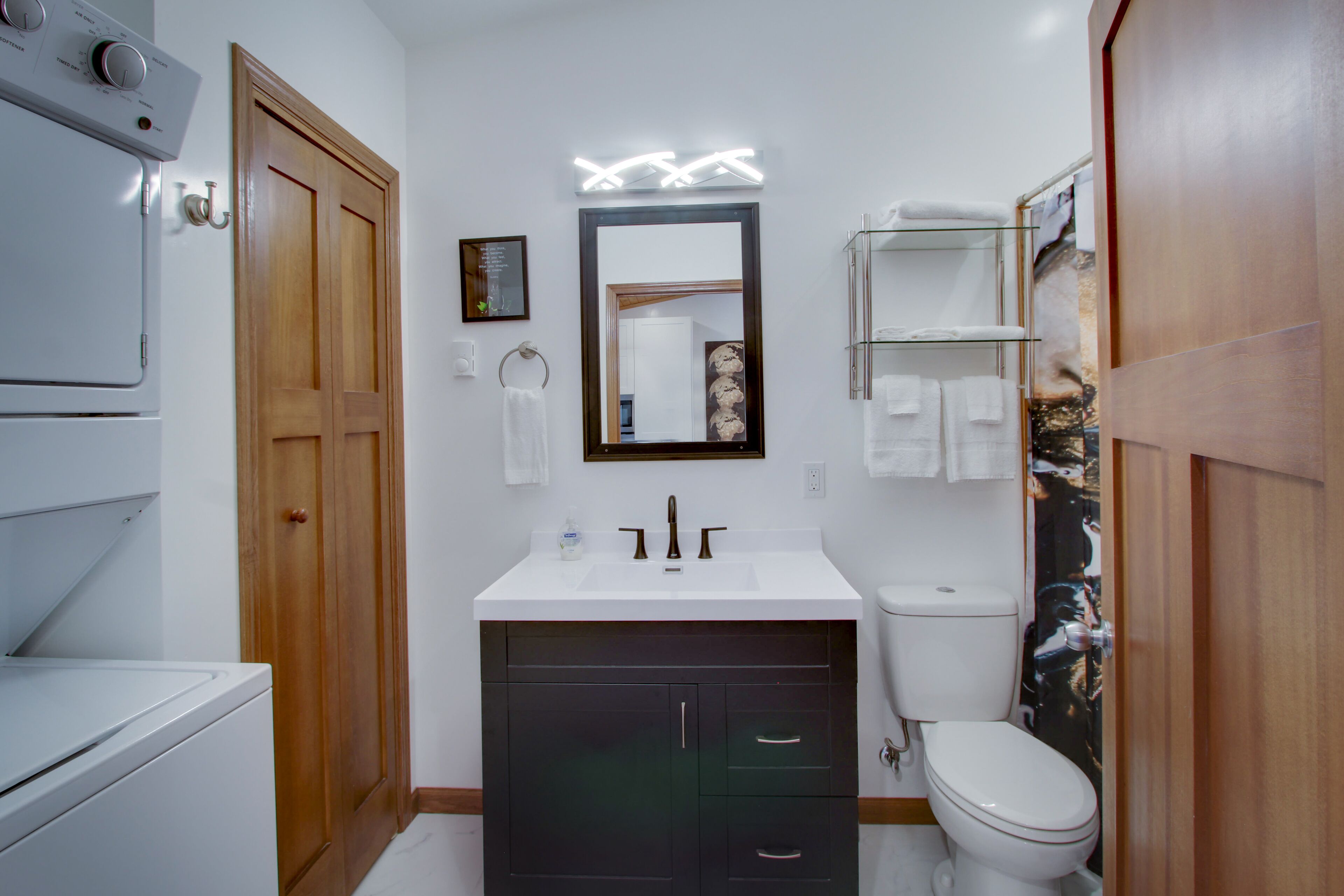 A bathroom with a white sink, a mirror, a toilet, and a shower area.