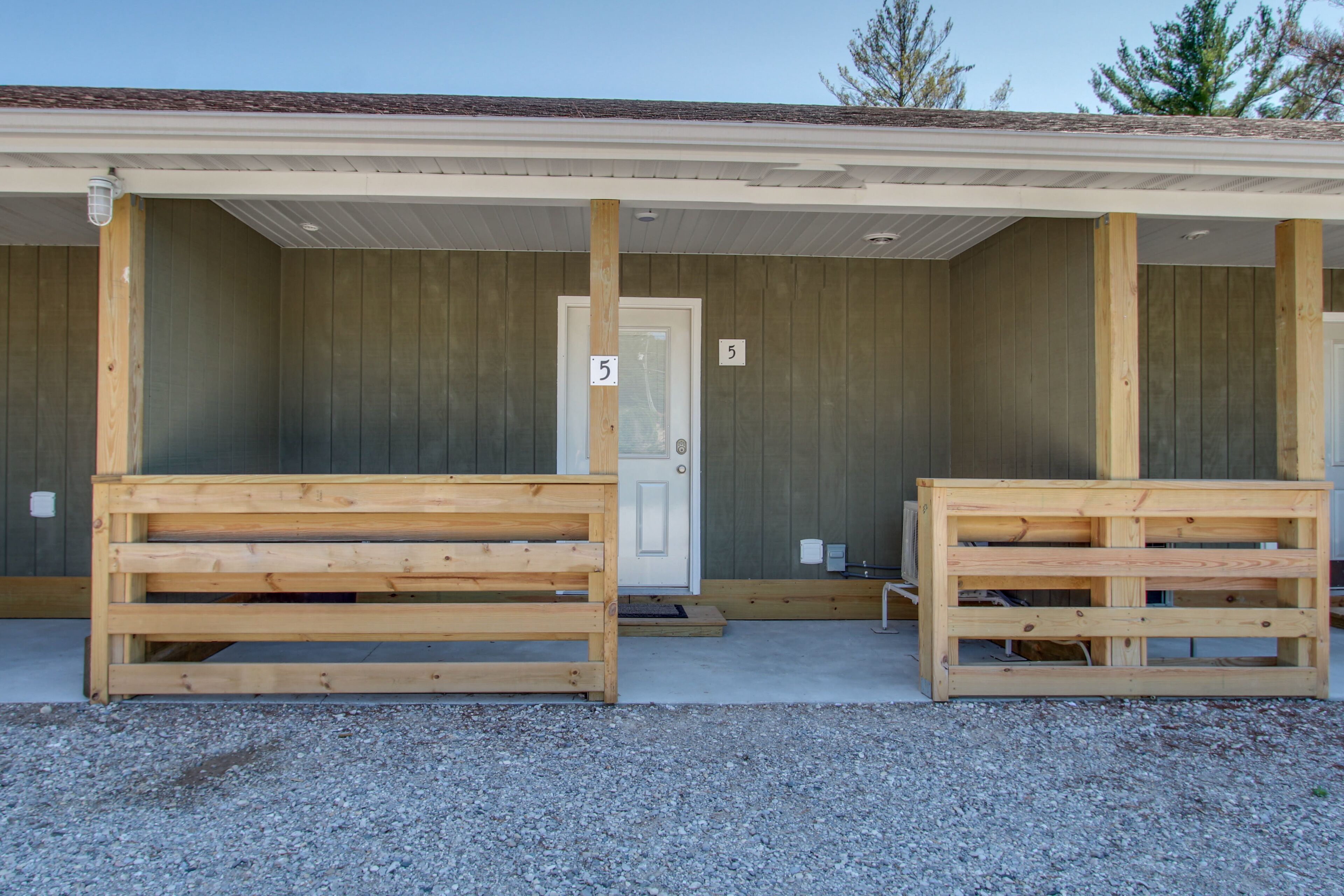 Un bâtiment doté d’un porche couvert, de bancs en bois et d’une porte portant le numéro 5.