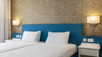 Hotellihuone, jossa on suuri sänky, kaksi yöpöytää ja kuvioitu seinä.