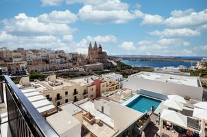 A rooftop pool area with a view of a historic building and coastline.