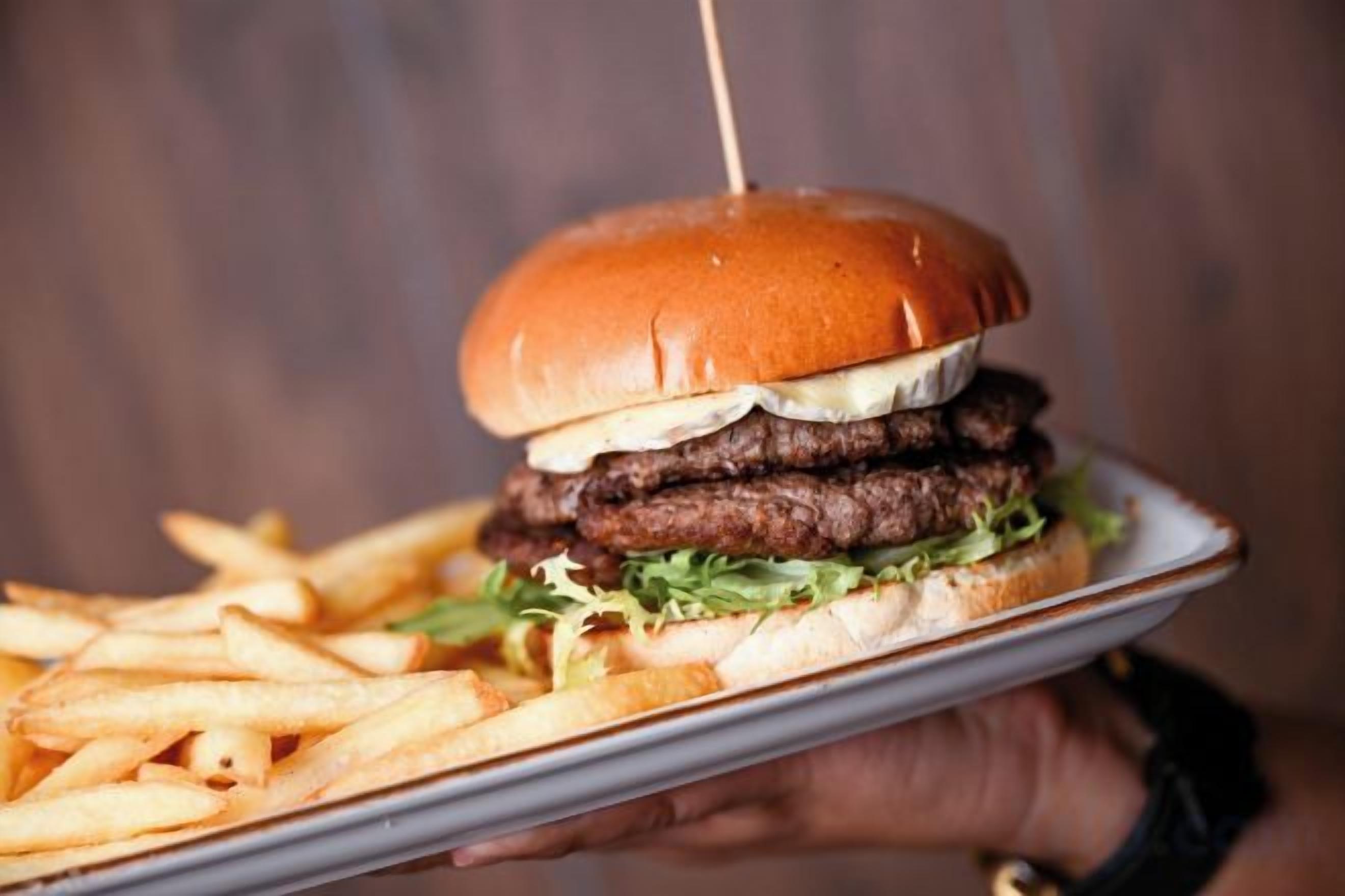 A person holding a plate with a burger and fries.