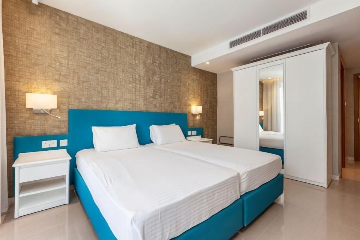 Ein Hotelzimmer mit einem großen Bett, Nachttischen, einem Kleiderschrank und einer Wand mit Ziegeloptik.