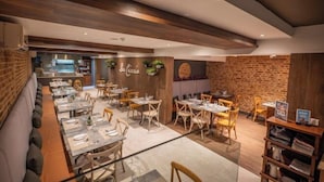 A restaurant with a modern interior, featuring wooden beams, brick walls, and a mix of wooden and upholstered seating. - Pergola Hotel & Spa (Mellieha)