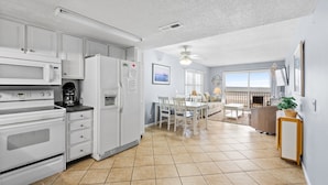 A modern kitchen with white appliances, a dining area with a table and chairs, and a balcony with a view.