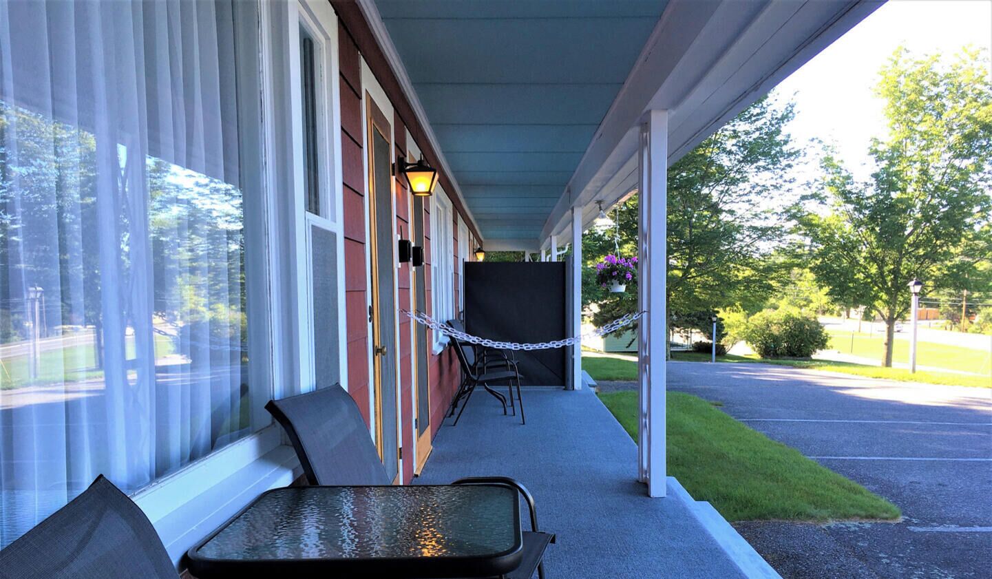 A covered porch with a table and chairs, a chain-link fence, and a sign stating "100% Smoke Free Property".