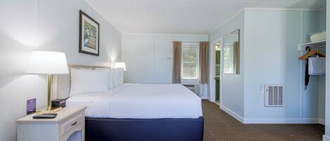A hotel room with a bed, bedside lamps, a nightstand, a wardrobe, and a window with curtains.