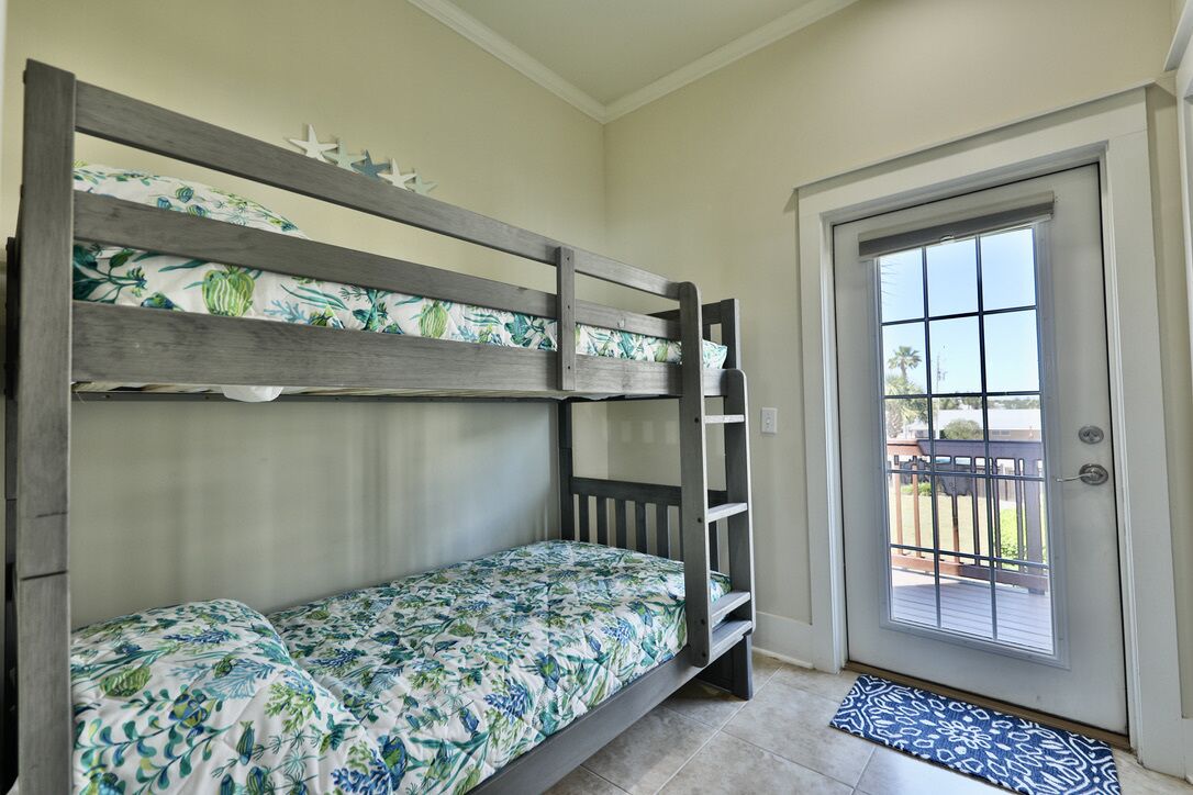A bunk bed with floral bedding, a door with a window, and a doormat.