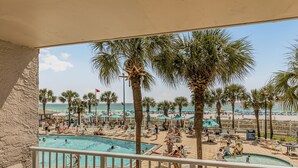 A pool area with lounge chairs and umbrellas, palm trees, and a view of the beach. - 2nd Floor @ THE SUMMIT 1BR 1.5 BA  Free Beach Chairs!  $240 Weekly Value (Panama City Beach)