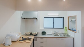 A modern kitchen with a stove, sink, and window. There are cabinets, a countertop, and a mirror above the sink.