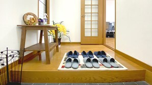 A hallway with a wooden bench, a welcome sign, a potted plant, and a pair of shoes on a mat.
