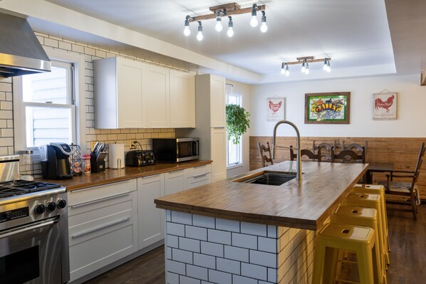 A modern kitchen with white cabinets, a wooden island, and bar stools.