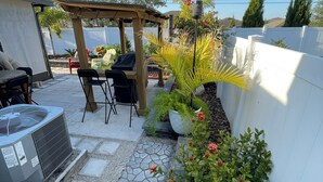 Ein Patio mit einer Pergola, Sitzmöbeln und einem Grill.