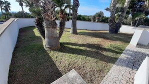 A landscaped area with palm trees, a paved walkway, and a white wall. - Superior apartment with view and garden (Santa Maria di Leuca)