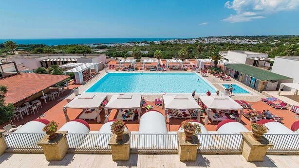 A rooftop pool area with multiple swimming pools, lounge chairs, and umbrellas. - Superior apartment with view and garden (Santa Maria di Leuca)