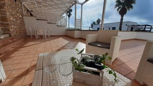 A rooftop patio with wicker furniture, a table with wine glasses, and a planter with plants. - Superior apartment with view and garden (Santa Maria di Leuca)