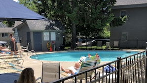Un área de piscina con sillones de descanso y una terraza cercada.