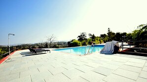 A rooftop pool area with a clear view of the surrounding landscape, including trees and distant hills. - The Sky Imperial Jungle Camp Resort (Kumbhalgarh)