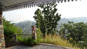 A stone structure with a red roof, surrounded by greenery and a view of distant hills. - The Sky Imperial Jungle Camp Resort (Kumbhalgarh)