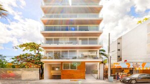 Un immeuble à plusieurs étages, doté d’une architecture moderne, avec des balcons aux étages supérieurs et une entrée au niveau du sol.
