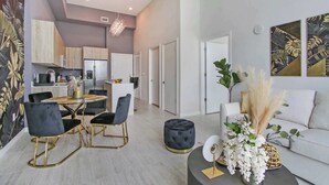 A modern living room with a dining area, featuring a sofa, chairs, and a coffee table. - One Bedroom Condo King Bed With City Views (Miami)