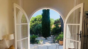 Quarto com uma grande janela em arco que dá para um jardim.