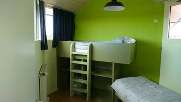 Ein Schlafraum mit Etagenbetten, einer Leiter, einem Fenster mit Vorhängen und einer Deckenleuchte.